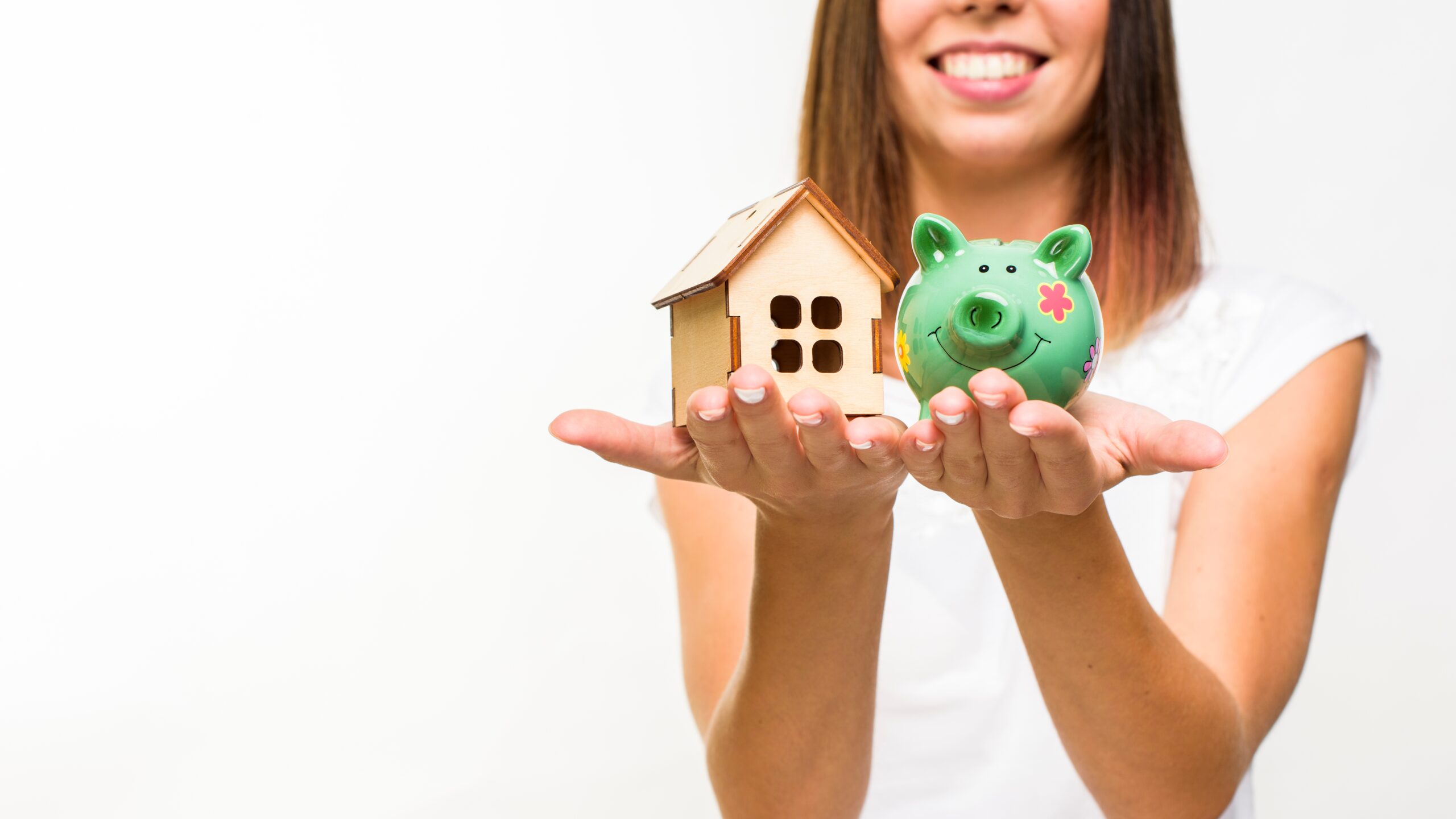 Uma mulher segurando um cofre e uma casa de brinquedo, representando fatores que ajudam na aprovação do financiamento imobiliário.