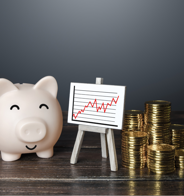 Imagem com um cofre em formato de porquinho, pilhas de moedas douradas e um gráfico ascendente. Ilustra a valorização dos imóveis financiados e o crescimento da renda gerada com aluguel ao longo do tempo, destacando a estratégia de investir para o futuro. Cofrinho e pilhas de moedas ao lado de gráfico de crescimento, representando valorização imobiliária e renda com aluguel.